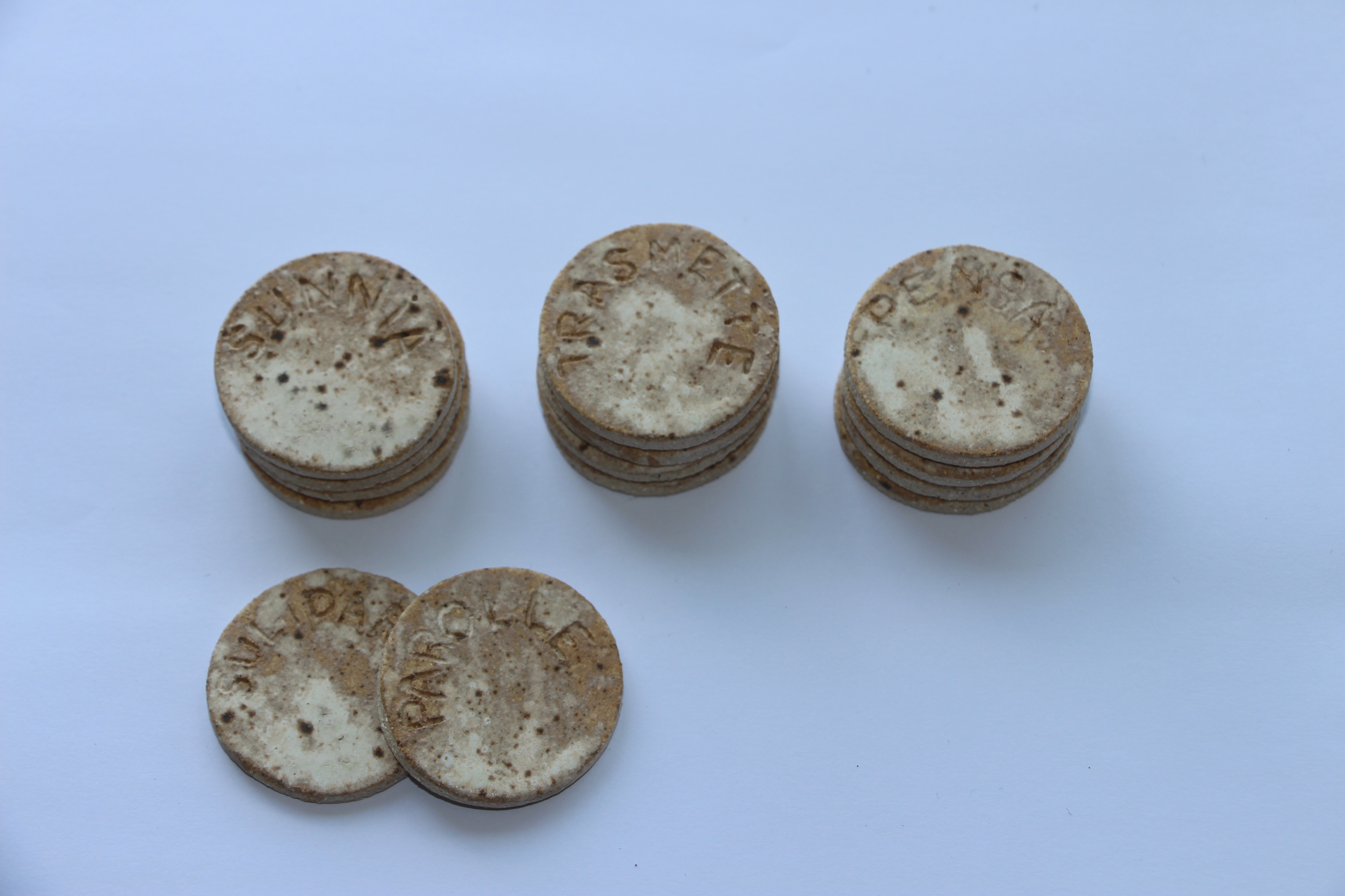 A collection of circular, flat items with textured surfaces, some stacked and others laid out, on a plain background.